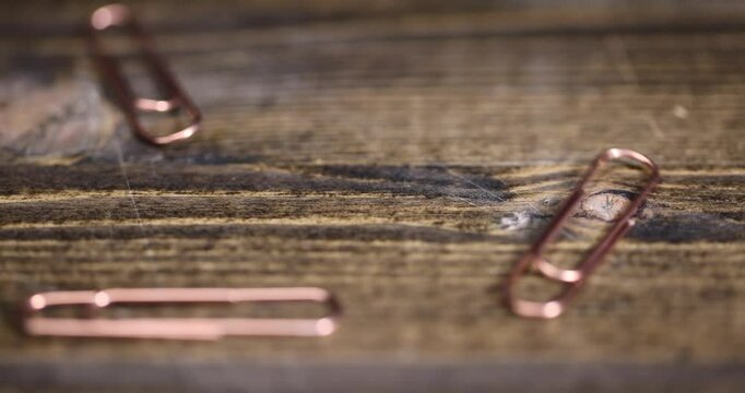 group of copper paper clips for the systematization of documents and paper, large-size copper paper clips close-up on the board