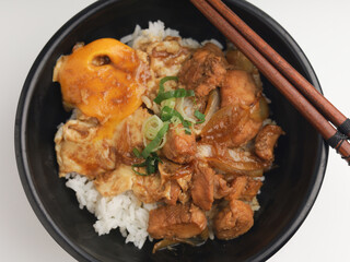Rice served with chicken teriyaki sauce and sunny side up egg in black bowl