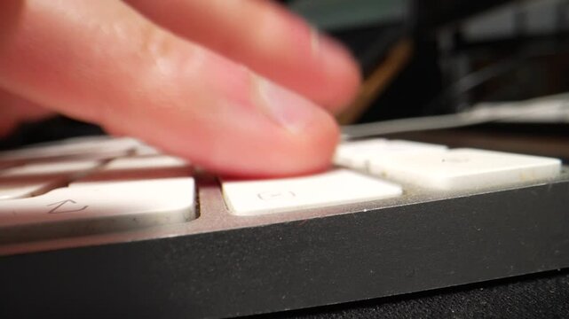 An extreme macro close-up of fingers typing on a white keyboard, then repeatedly hitting the delete key