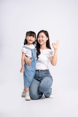 Full body image of Asian mother and daughter posing on white background