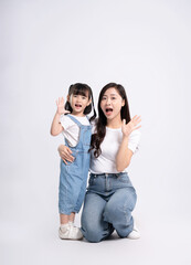 Full body image of Asian mother and daughter posing on white background