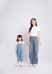 Full body image of Asian mother and daughter posing on white background