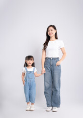 Full body image of Asian mother and daughter posing on white background