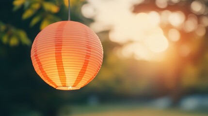 Obraz premium A vibrant paper lantern glows softly in a serene outdoor setting, illuminated by the warm light of a sunset, surrounded by greenery.