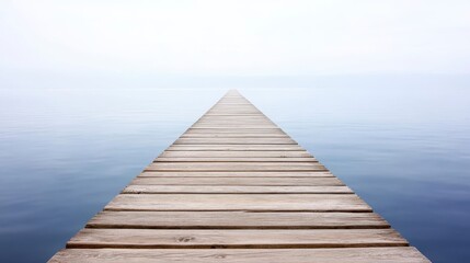 Obraz premium A serene wooden pier extends into calm waters, shrouded in mist, creating a tranquil and dreamy atmosphere.