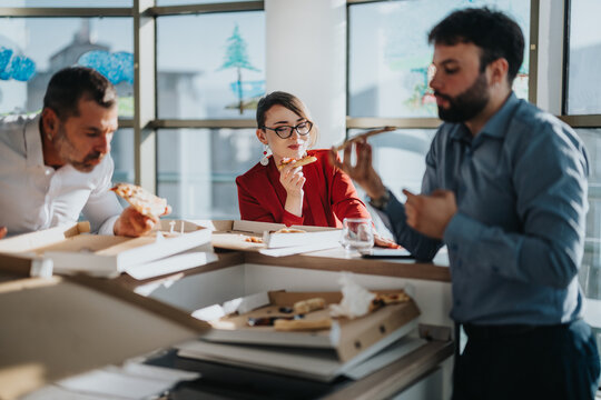 Multicultural business employees enjoy a casual pizza lunch together at the office. The relaxed setting fosters teamwork and camaraderie, highlighting diverse team dynamics.