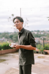 A Southeast Asian man enjoying a sip of coffee on a peaceful morning