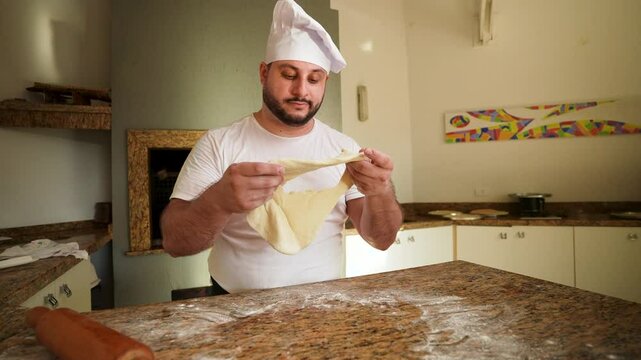 A professional chef holds failed dough in their hands, expressing frustration and disappointment in a kitchen setting