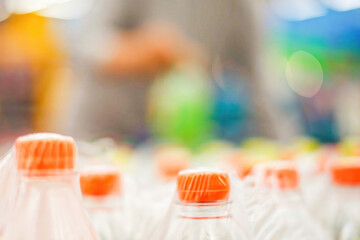Orange plastic bottle caps on a blurred supermarket background