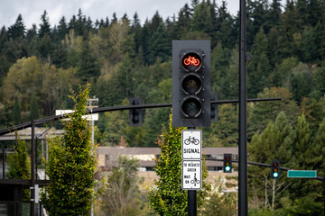 Traffic light and traffic symbols on street signs in a suburban setting, red light for bikes, white sign with bicycle travel information, transportation background
