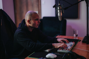 Dedicated individual working in a home studio environment, using a microphone and keyboard. The setup suggests pod casting or streaming activities, highlighting creativity and digital content creation