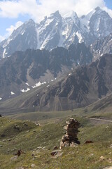 stone pile in the meadow of himalayas with series of snow covered mountains in the background © deepak
