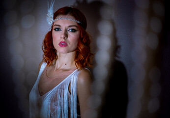 A young woman with red hair, dressed in stylish white clothing reminiscent of 1920s fashion. Her...