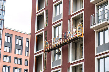 Construction scaffold suspended in front of a modern building facade with windows, showcasing exterior renovation work