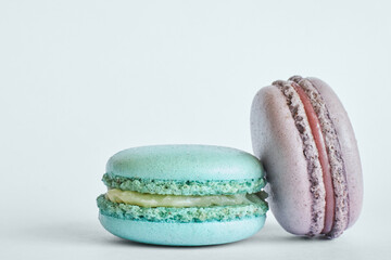Two colorful French Macarons, cakes with different flavors, mint, apple, currant flavor. dessert, macaroons aquamarine, green, purple color. Copy space for text, close up