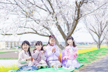 桜の木の下でピクニックをする小さな女の子たち