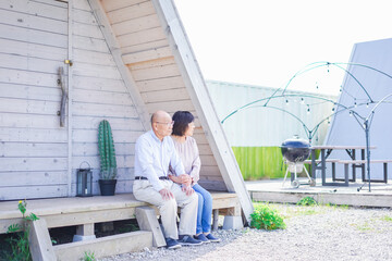 別荘の前に座るシニアの夫婦