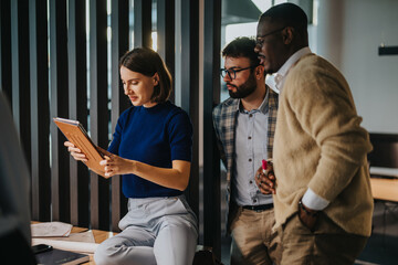 A multicultural group of business people gathers around a tablet, brainstorming and discussing...