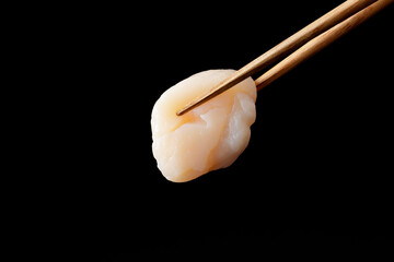 箸で持ち上げた帆立の貝柱の刺身