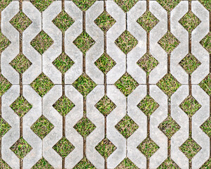 Geometric concrete paving stones with grass-filled gaps, arranged in a repetitive pattern on a flat surface. Seamless texture