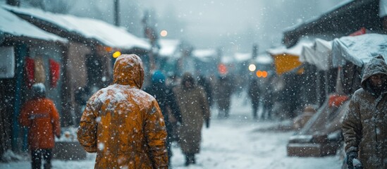 A man in a yellow jacket walks through a snowy city street.