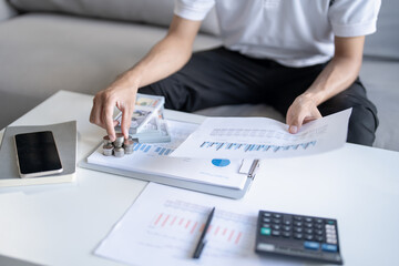 Saving money. Man calculate finances home pay bills taxes savings economy financial at home and saving money stacking coins with calculator