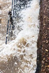 Heavy storm surge waves washing over concrete steps and iron railings on sea wall