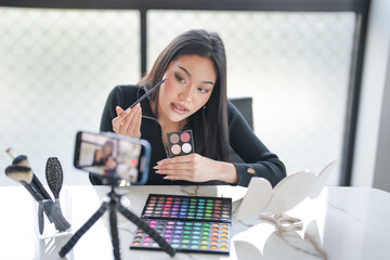 Asian girl makeup artist Professional Woman blogger vlogger is showing cosmetics products with...