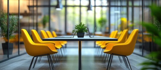 A modern meeting room with yellow chairs and a black table in the center, with a plant in the background.