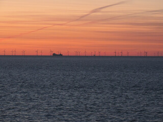 Dutzende Windr&auml;der in einem Windpark auf offenem Meer im Zwielicht