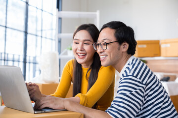 Obraz premium Happy young Asian couple with laptop at home.