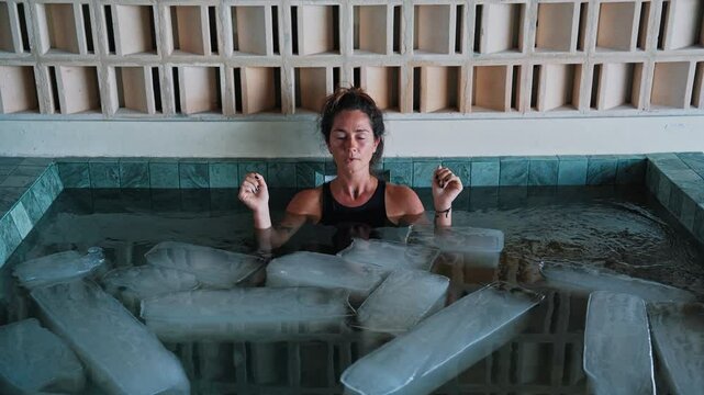 Healthy Woman Diving into Cold Water of Swimming Pool with Ice Cubes for Body Health. Pretty Person in Icy Bathtub Full of Frosty Aqua for Wellbeing. Extreme Exercise of One Swimmer in Freezing Bath