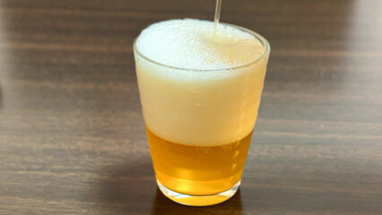 グラスに生ビールを注ぐ　黄金色の麦酒とあふれる泡
