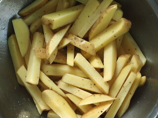 potato wedges and sticks tossed with oil and herb for roasting