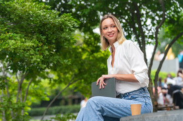 Obraz premium Caucasian Woman Sitting and Using Tablet While Having a Cup of Coffee Outdoor a Park