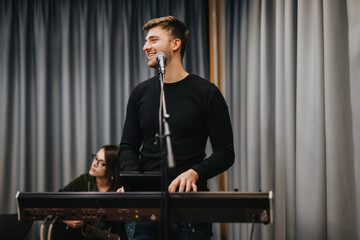 A talented musician joyfully performing at a live event, playing the keyboard. The casual and engaging atmosphere is enhanced by a guitarist accompanying in the background. Perfect for music or