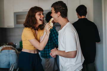 Lively group of friends sharing laughter and playful moments while preparing food in a cozy kitchen setting.