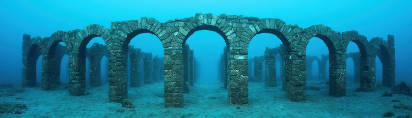 Ancient underwater ruins featuring arches surrounded by serene blue waters.