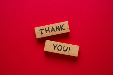 Thank you is written on wooden blocks standing on a red background