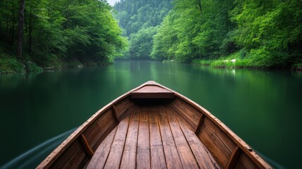 Obraz premium Wooden boat gliding on a serene green river through lush forest