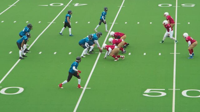 Diverse Group of Male Athletes Competing in an Intense American Football Game on a Green Field, Showing Teamwork and Strategy. Players in Red and Blue Jerseys Engage in Dynamic Plays and Formations