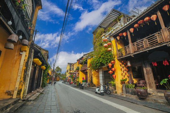 Streets with traditional old yellow houses decorated with paper lanterns in Hoi An