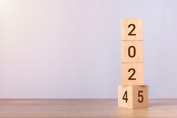 2024 change to 2025 wooden cube blocks on blue background. Resolution, plan, review, goal, start, end year and New Year concepts