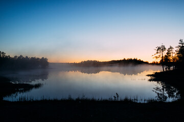 Tranquil Lake Reflection at Sunrise with Misty Horizon