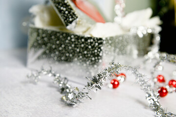Close-up of silver polka dot gift box with tinsel, red ornaments