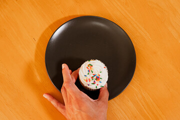 Hand grabbing last cupcake from plate on table