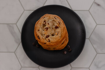 Stack of chocolate chip cookies on black plate in kitchen