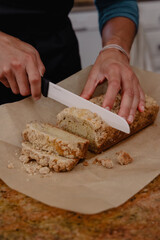 Female baker cutting coffee cake loaf on pastry paper