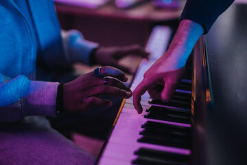 A close-up of diverse musicians working together on a piano, highlighting creativity and collaboration in a studio environment filled with music and passion.