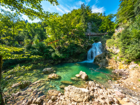 Tourists walking on bridge over waterfall at tolmin gorges in slovenia